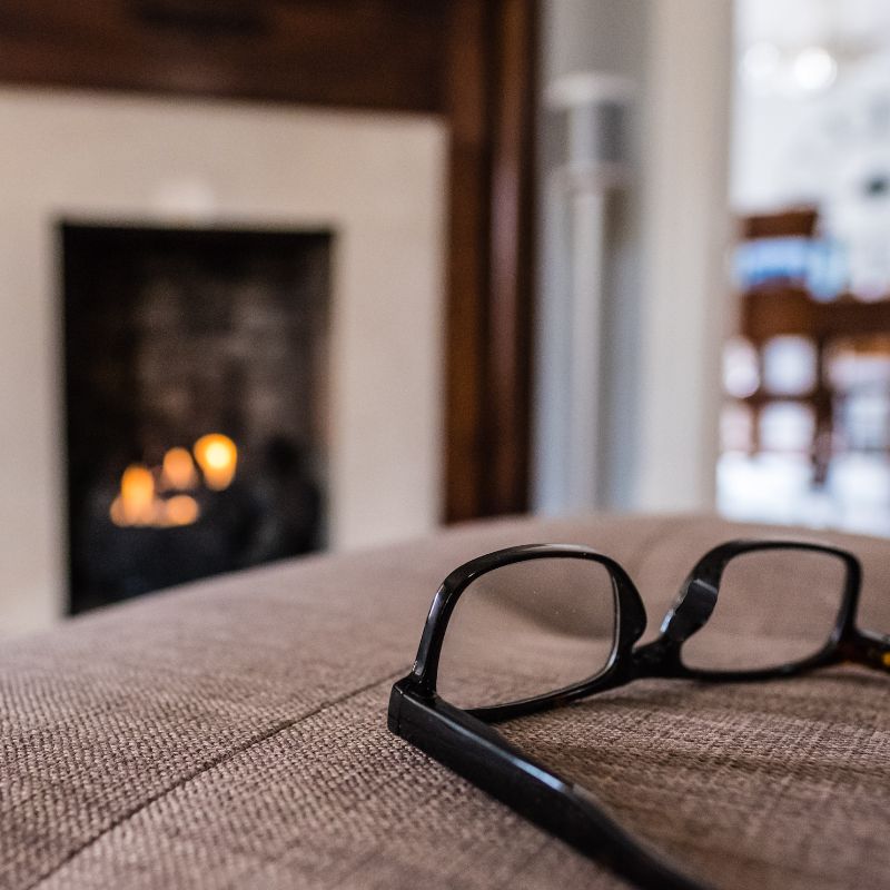 black eye glasses on a couch or chair cushion with a burning fireplace in the background